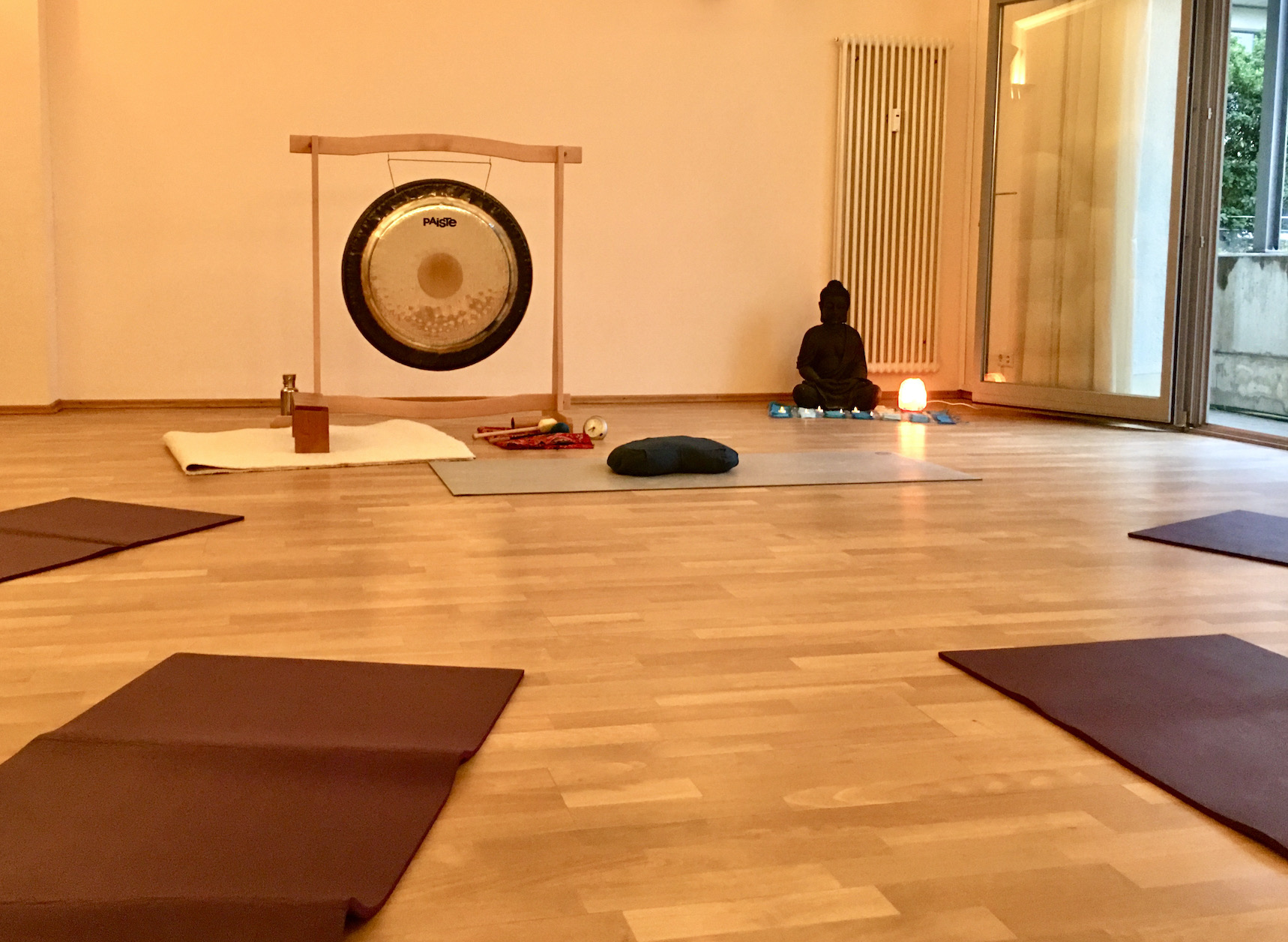 Gong steht im Yoga-Studio mit Yoga-Matten im Vordergrund